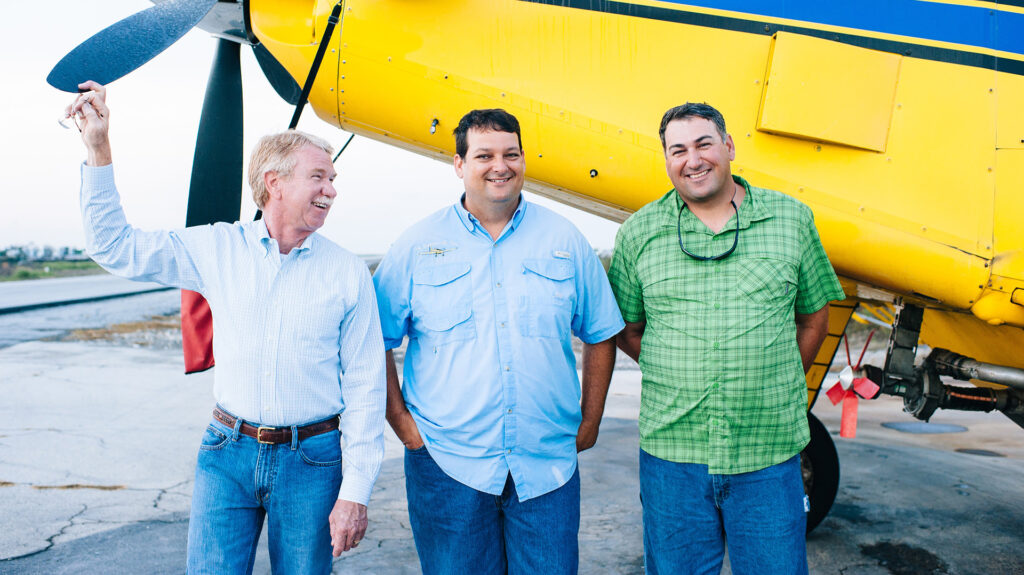 Sumersill family in front of an Air Tractor aircraft, showcasing the teamwork and camaraderie in agricultural aviation. The image highlights the close-knit community of pilots and operators dedicated to crop spraying and aerial application services.
