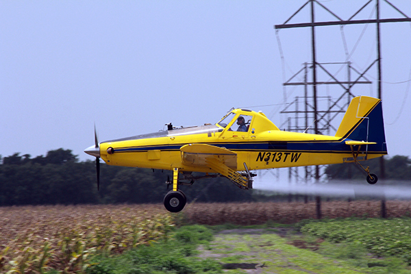 Air Tractor AT-502B agricultural aircraft in flight over a cornfield, showcasing its capabilities in crop dusting and aerial application.