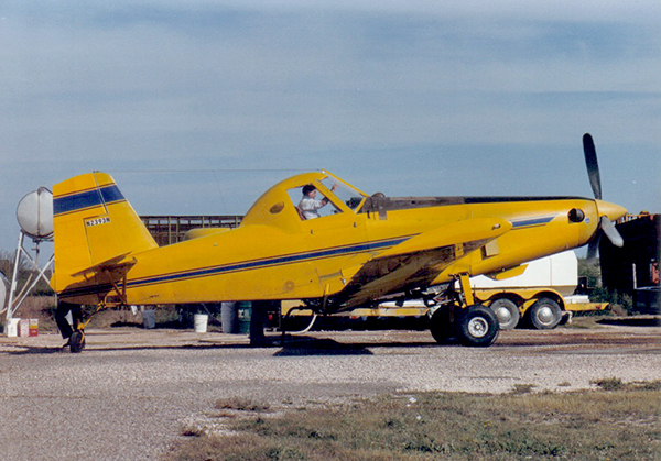 Air Tractor AT-502B agricultural aircraft on the ground, featuring a single-engine design and equipped for crop dusting. The pilot is visible in the cockpit, showcasing the plane's operational capabilities in agricultural aviation.
