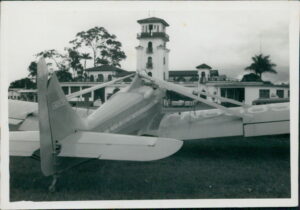 Air Tractor AT-502B airplane parked with a control tower and foliage in the background, showcasing its agricultural design.