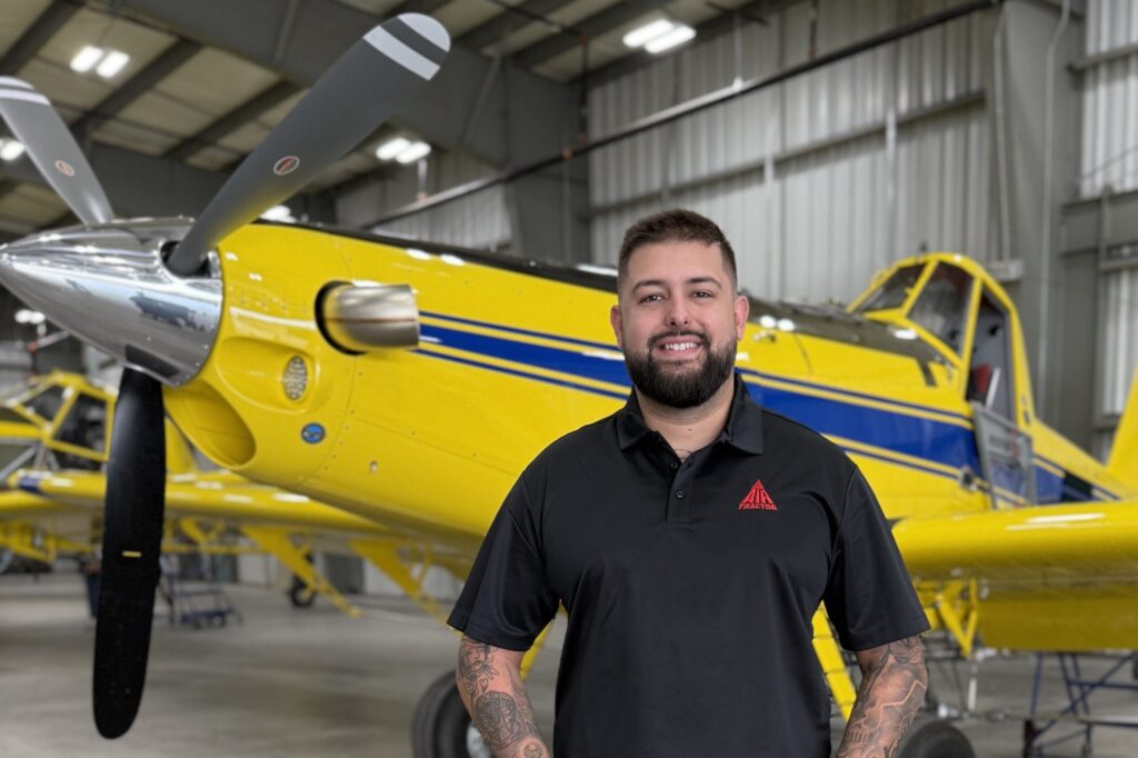 Air Tractor employee standing in front of an Air Tractor AT-502B agricultural aircraft in a hangar, showcasing the aircraft's features and design.