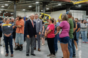 Air Tractor employees meet Congressman Roger Williams in Olney, featuring the AT-802 and AT-502 aircraft models in the background. The gathering highlights community engagement and appreciation for agricultural aviation.