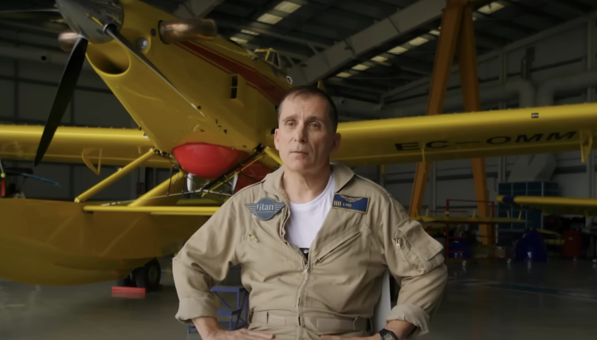 Titan pilot seated in front of an Air Tractor AT-802F in a hangar giving an interview about training, showcasing firefighting technology and operations.