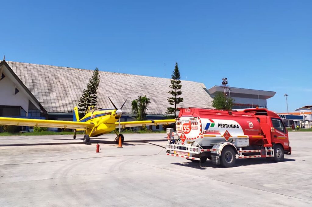 Air Tractor agricultural aircraft refueling at an airstrip, showcasing its robust design and versatility for crop dusting and aerial application. A fuel truck from Pertamina is visible in the foreground.