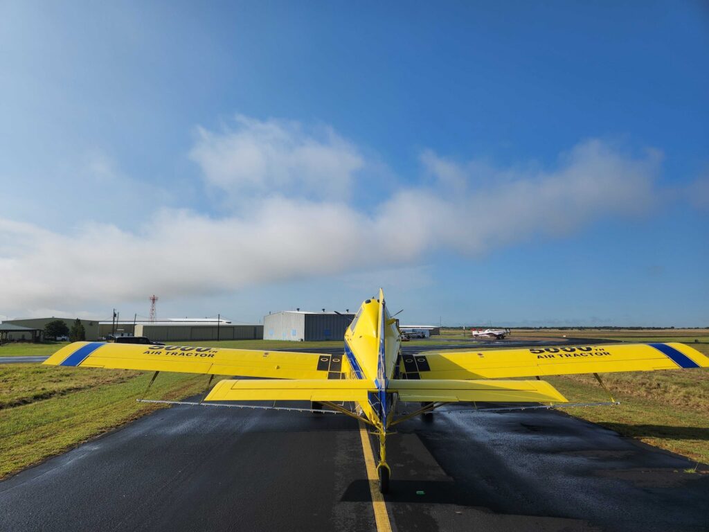 Air Tractor 500, a specialized agricultural aircraft, parked on the runway with a clear sky in the background. The plane is designed for efficient crop dusting and aerial application, showcasing its robust build and functional design.