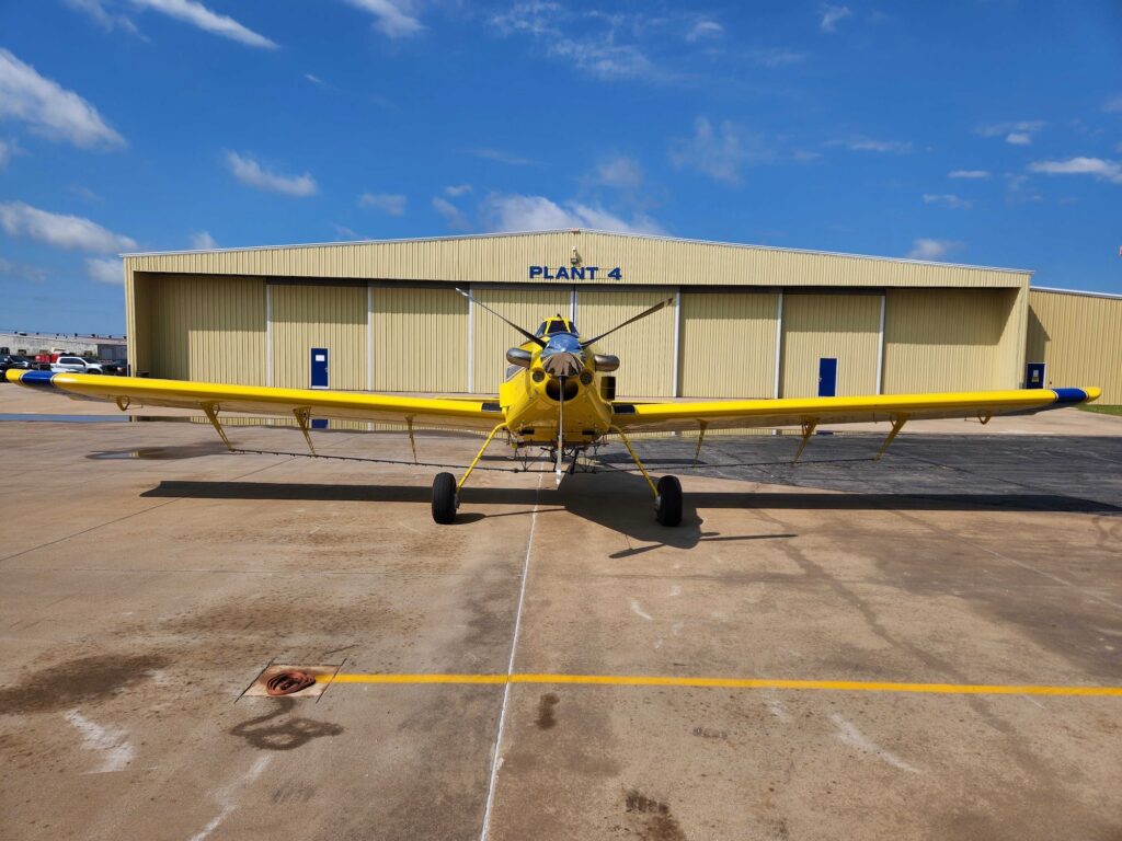 Air Tractor AT-502B agricultural aircraft parked in front of a hangar, showcasing its robust design and large wingspan, ideal for crop dusting and aerial application.