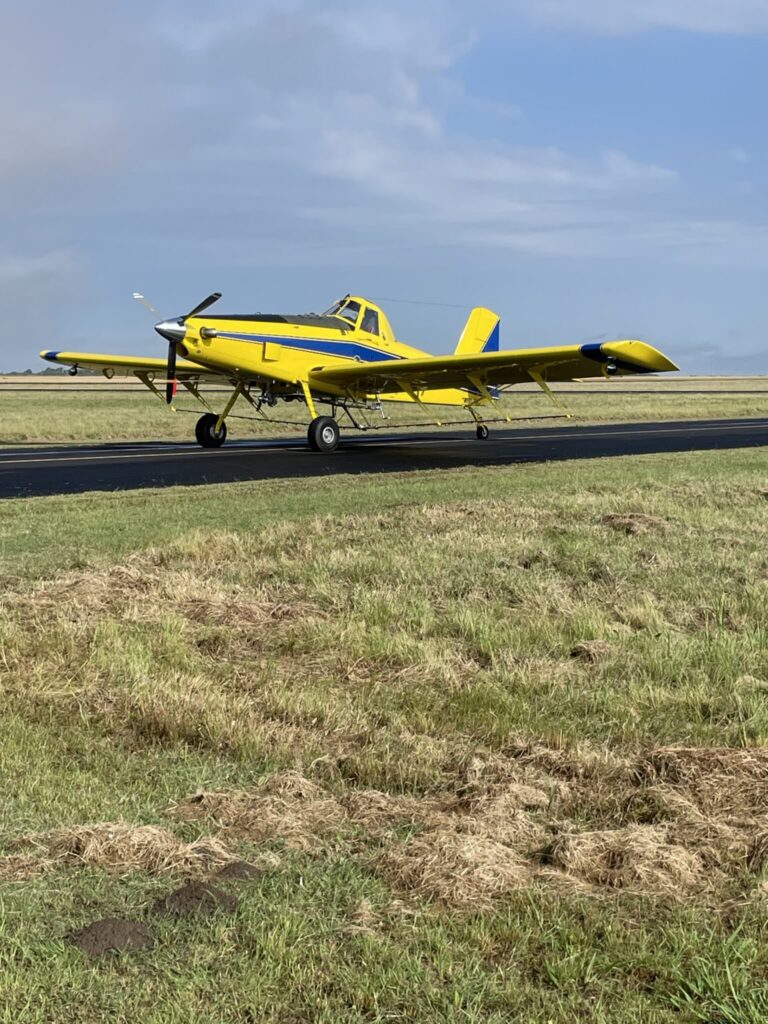 Air Tractor AT-502B agricultural aircraft on the runway, designed for crop dusting and aerial application. The plane features a high-wing design and is equipped with a powerful engine, showcasing its capabilities for efficient farming operations.